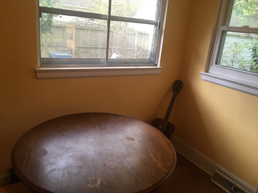 A photo of the same brown table in the same yellow room cleaned and completely void of items.