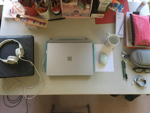 The author's desk, which includes neatly-organized headphones, a laptop, pens, and a coffee mug. 