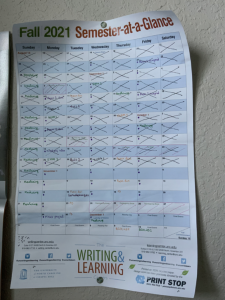 My copy of the Learning Center Semester-at-a-Glance calendar. The calendar is hanging on my wall. I have crossed out each day. The calendar is complete with notations for when my exams and large assignments are due this term. 