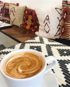 A coffee sitting on a table with pillows in the background