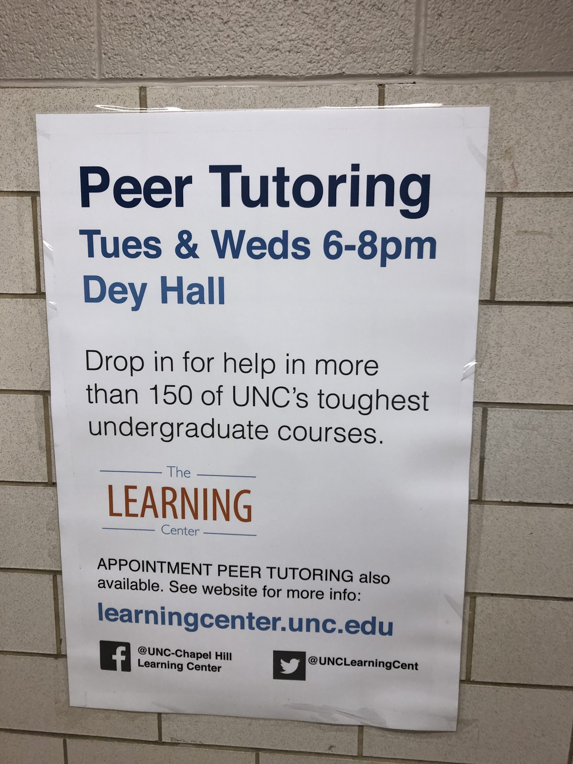 A white poster against a brick wall in Dey Hall. The poster advertises drop-in Peer Tutoring from 6-8 pm in Dey Hall every Tuesday and Wednesday. 