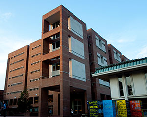 A four story brick building with large windowns in each corner facing the main campus. 