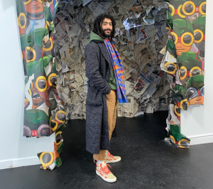 a picture of Rory Allen Philip Ferreira, a very stylish person standing in front of a colorful art piece